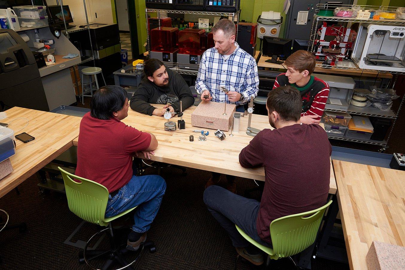un instructor enseña a estudiantes con materiales didácticos impresos en 3D