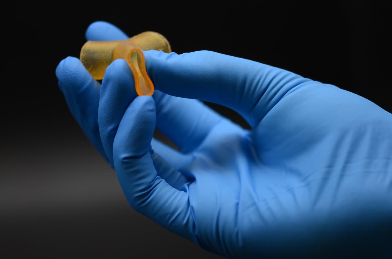Blaue behandschuhte Hand, die ein 3D-Druckteil drückt