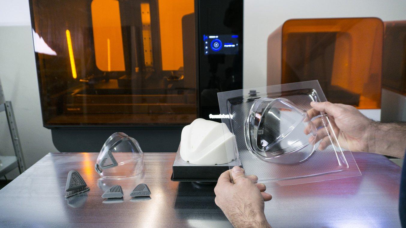 L’insieme dei modelli stampati in 3D e termoformati che assemblati formeranno la G-mask, ordinati su un tavolo da lavoro.