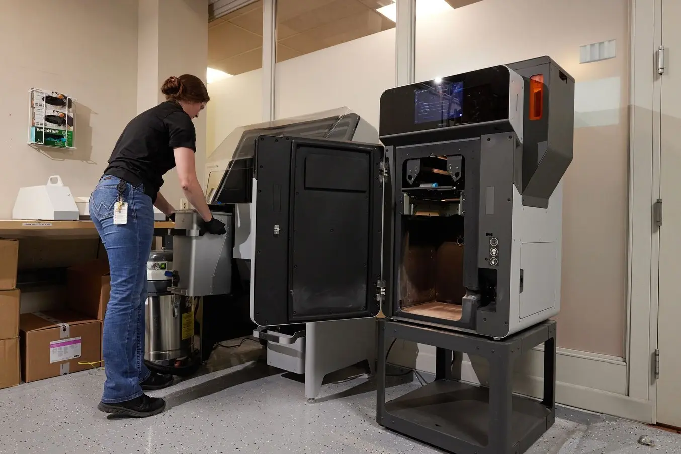 a female eaton employee pulls a build chamber from the Fuse printer and gets ready to insert it into the Fuse Sift